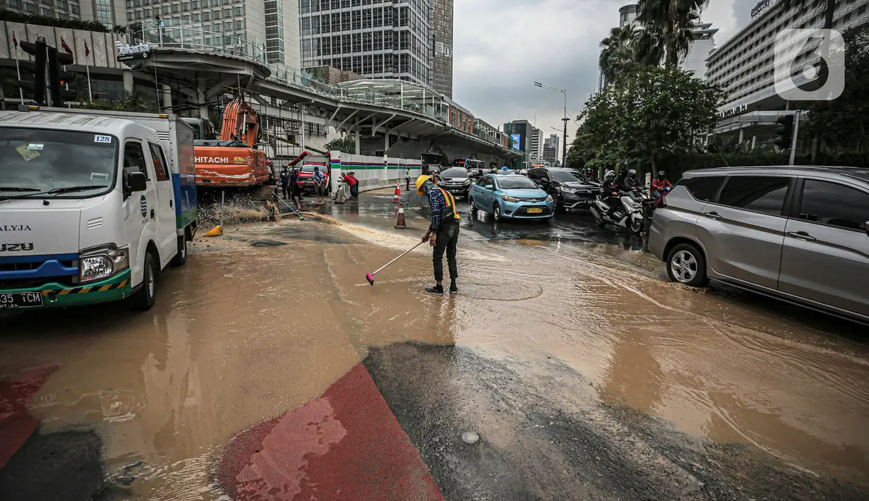 Petugas membersihkan jalan dari genangan air akibat kebocoran saluran pipa air di kawasan Bundaran Hotel Indonesia (HI), Jakarta, Selasa (11/10/2022). Kebocoran pipa air diduga terimbas proyek revitalisasi Halte Bundaran Hotel Indonesia. (Liputan6.com/Faizal Fanani)