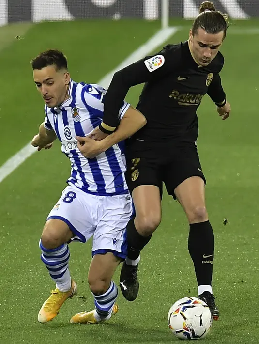 Penyerang Barcelona, Antoine Griezmann berebut bola dengan pemain Real Sociedad, Andoni Gorosabel pada pertandingan La Liga Spanyol di stadion Reale Arena, Spanyol, Senin (22/3/2021). Barcelona kini mengemas 62 poin dari 28 kali berlaga dan berhak menempati posisi kedua. (AP Photo/Alvaro Barrientos)
