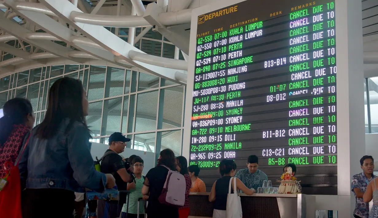 Sejumlah penumpang mencari informasi jadwal penerbangan di Bandara Ngurah Rai, Bali, Jumat (29/6). PT Angkasa Pura I menutup sementara operasional bandara selama 16 jam dikarenakan dampak abu vulkanik Gunung Agung. (AFP/GEDE ARDIASA)