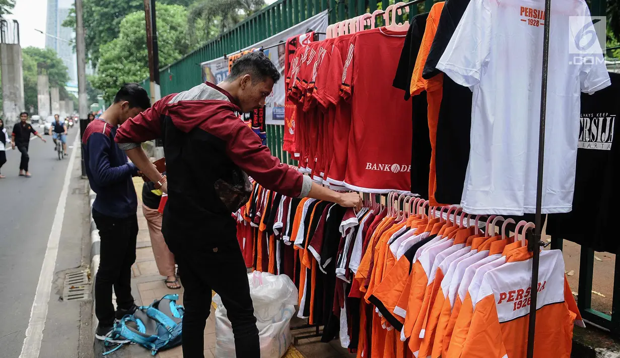 Suporter melihat atribut Persija di kawasan Senayan, Jakarta, Minggu (9/12). Pedagang memanfaatkan momen pertandingan Persija Jakarta yang akan bertanding melawan Mitra Kukar. (Liputan6.com/Faizal Fanani)
