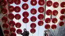 Seorang pekerja memasang lentera tradisional Tiongkok di sepanjang gang menjelang Tahun Baru Imlek di Beijing, China, 2 Februari 2021. Imlek tahun ini jatuh pada tanggal 12 Februari 2021. (NOEL CELIS/AFP)