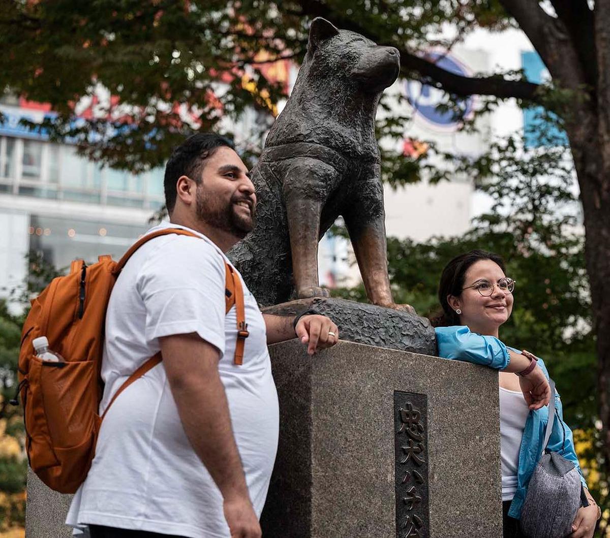 Orang-orang berpose untuk berfoto di samping patung Hachiko di depan Stasiun Shibuya, Tokyo, Senin (6/11/2023). Hachiko, anjing yang populer di kalangan pelancong Jepang, akan berusia 100 tahun pada November 2023 ini. Yuk, simak kembali kisahnya yang biki