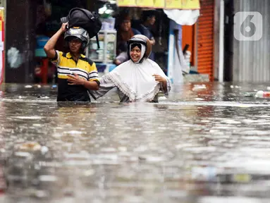 Warga melintasi genangan banjir yang melanda kawasan Kemang Utara, Jakarta, Kamis (4/1/2024). (Liputan6.com/Herman Zakharia)