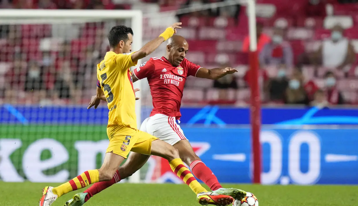 Gelandang Benfica, Joao Mario berebut bola dengan gelandang Barcelona, Sergio Busquets pada pertandingan grup E Liga Champions di stadion Luz di Lisbon, Portugal, Kamis (30/9/2021). Kemenanga atas Barcelona membuat Benfica berada di posisi kedua klasemen. (AP Photo/Armando Franca )