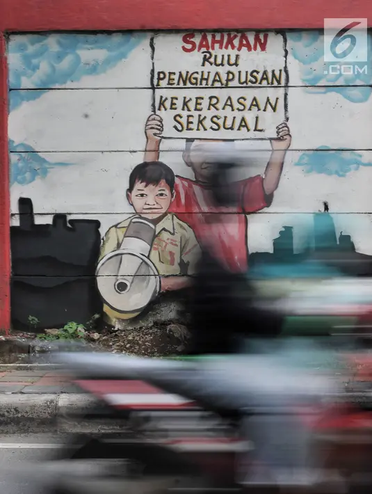 Pengendara melintasi mural bertema 'Tolak Kekerasan Perempuan dan Pelecehan Seksual' di kawasan Jatinegara, Jakarta, Senin (17/12). Mural tersebut dibuat untuk meningkatkan kesadaran akan ancaman bahaya pelecehan seksual. (Merdeka.com/Iqbal S. Nugroho)