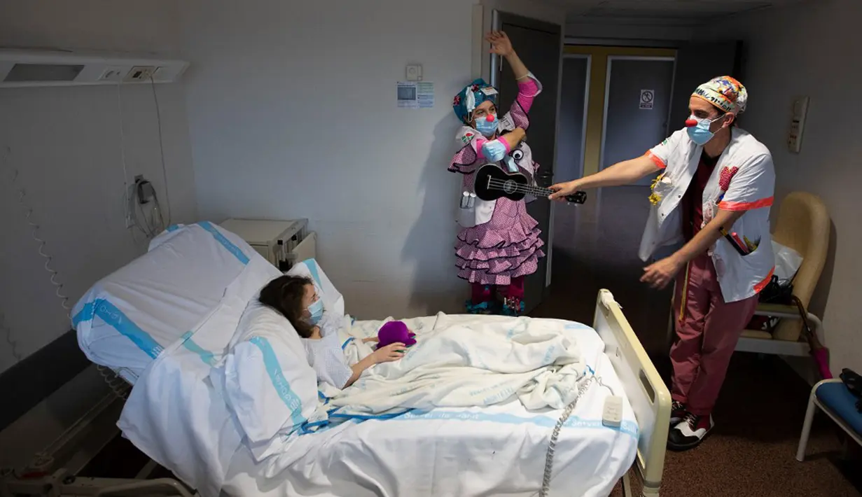 Dua badut dari LSM Sunrise Media (Senyuman Medis) tampil untuk pasien Iris berusia sembilan tahun di sayap anak-anak Rumah Sakit Son Llatzer, Palma de Mallorca, Spanyol, 8 Maret 2021. (JAIME REINA/AFP)