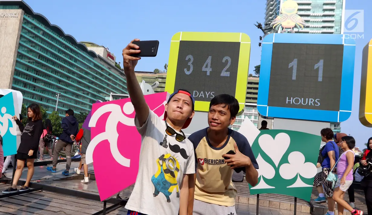 Warga swafoto dengan latar layar Countdown Asian Games 2018 saat Car Free Day di Bundaran HI, Jakarta, Minggu, (10/09). Rencananya pelaksanaan Asian Games 2018 akan dilaksanakan di Jakarta dan Palembang. (Liputan6.com/Fery Pradolo)