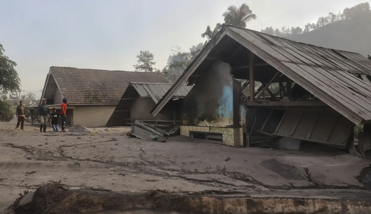 Penduduk desa memeriksa kerusakan saat rumah terlihat terkubur abu vulkanik dari letusan Gunung Semeru di desa Kajar Kuning di Lumajang, Jawa Timur, Indonesia, Senin, 5 Desember 2022. Gunung berapi tertinggi di Indonesia pada hari ini Senin (5/12/2022), masih mengeluarkan awan panas guguran dengan amplitudo 25 mm dan lama gempa 386 detik. (AP Photo/Imanuel Yoga)