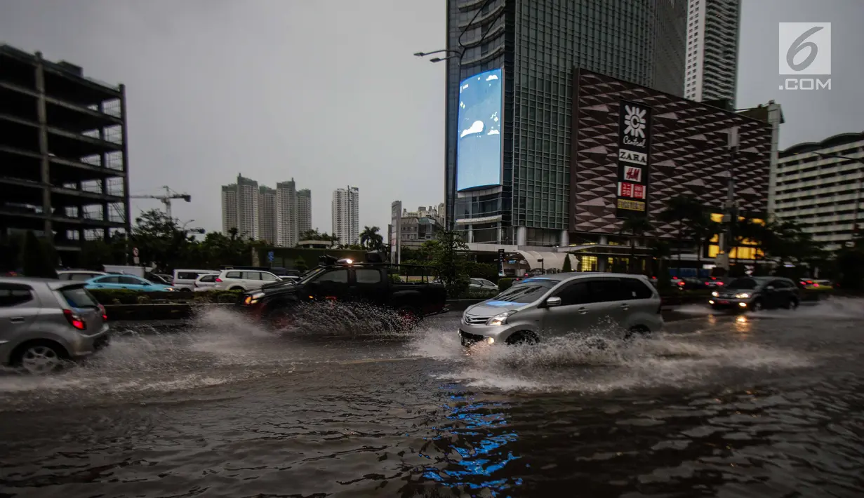 Kendaraan menerobos genangan air di kawasan MH Thamrin, Jakarta, Senin (11/12). Hujan lebat yang mengguyur wilayah Jakarta dan sekitarnya mengakibatkan air setinggi 15 cm menutupi sebagian badan jalan di kawasan tersebut. (Liputan6.com/Faizal Fanani)