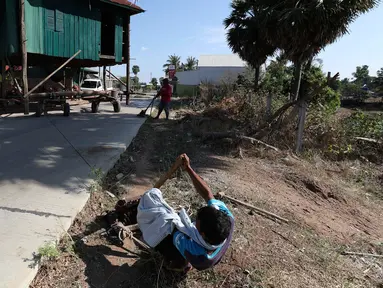 Seorang pria menarik rumah kayu ke tempat di desa Pon Sang di sisi utara Phnom Penh, Kamboja (26/4/2020). Ini adalah cara bergerak tradisional yang dikumpulkan oleh penduduk desa untuk saling membantu dengan menggunakan traktor dan batang kayu. dengan menjaga rumah tetap utuh. (AP/Heng Sinith)