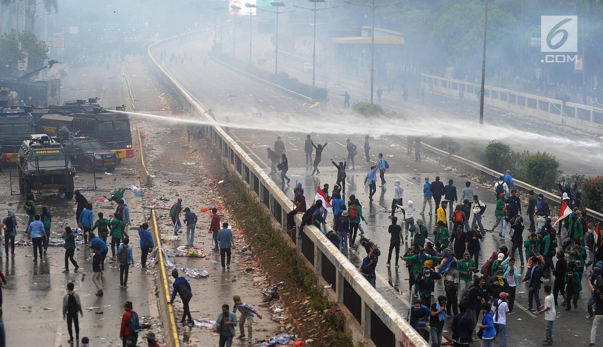 Polisi menyemprotkan air menggunakan water cannon ke arah mahasiswa saat demonstrasi menolak pengesahan RUU KUHP dan revisi UU KPK di depan Gedung DPR, Jakarta, Selasa (24/9/2019). Polisi menyemprotkan air ke arah mahasiswa karena menolak untuk dibubarkan. (merdeka.com/Arie Basuki)