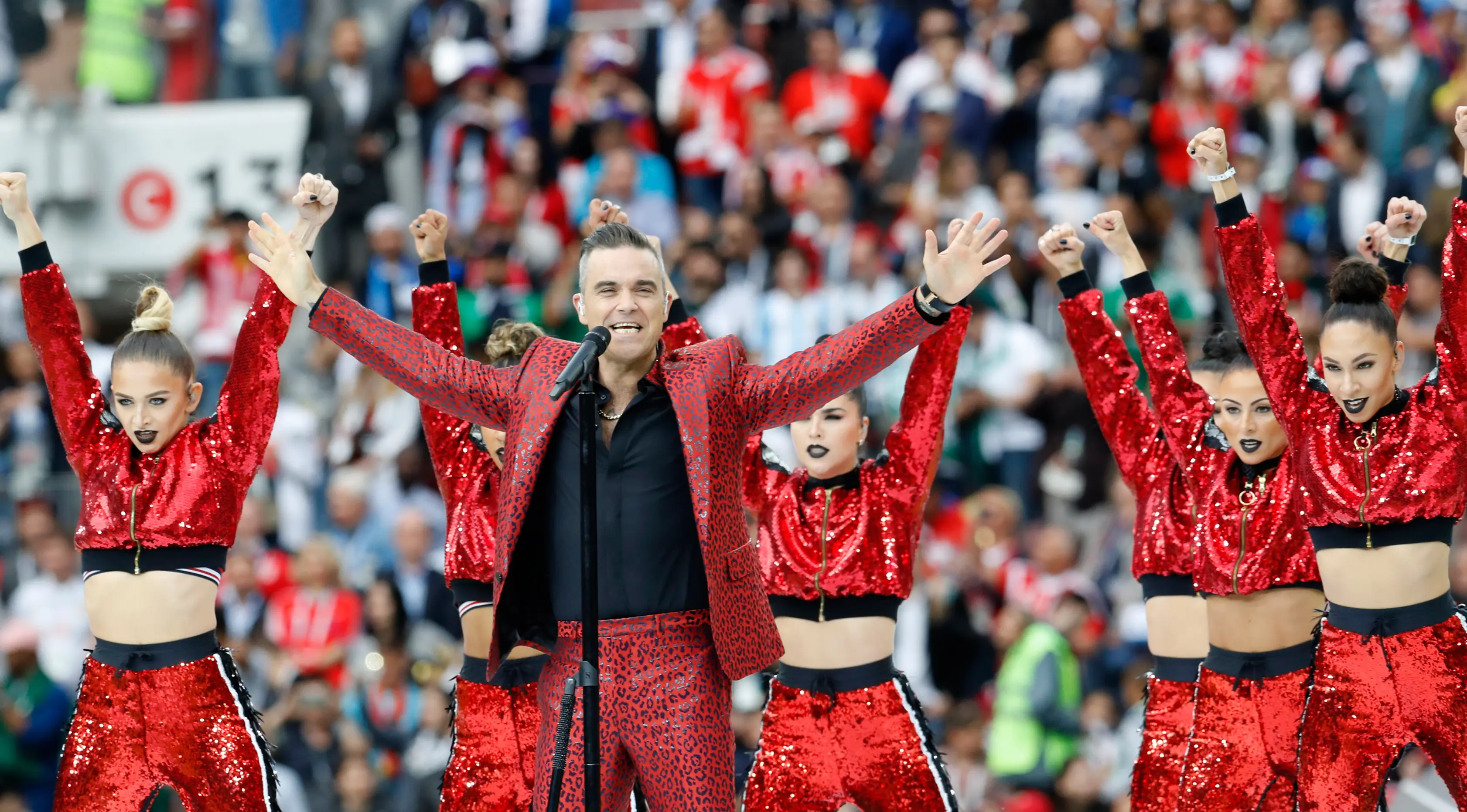 Penampilan penyanyi Inggris, Robbie Williams pada upacara pembukaan Piala Dunia 2018 di Stadion Luzhniki, Moskow, Kamis (14/6). Robbie dikelilingi para penari dengan atasan berkilauan merah terang yang menambah meriah penampilan. (AP/Antonio Calanni)