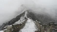Tembok Besar China terlihat setelah hujan salju ringan di Jiankou, utara Beijing pada Minggu (9/1/2022). Jalur pada Tembok Besar China itu pun terlihat memutih akibat salju. (GREG BAKER / AFP)