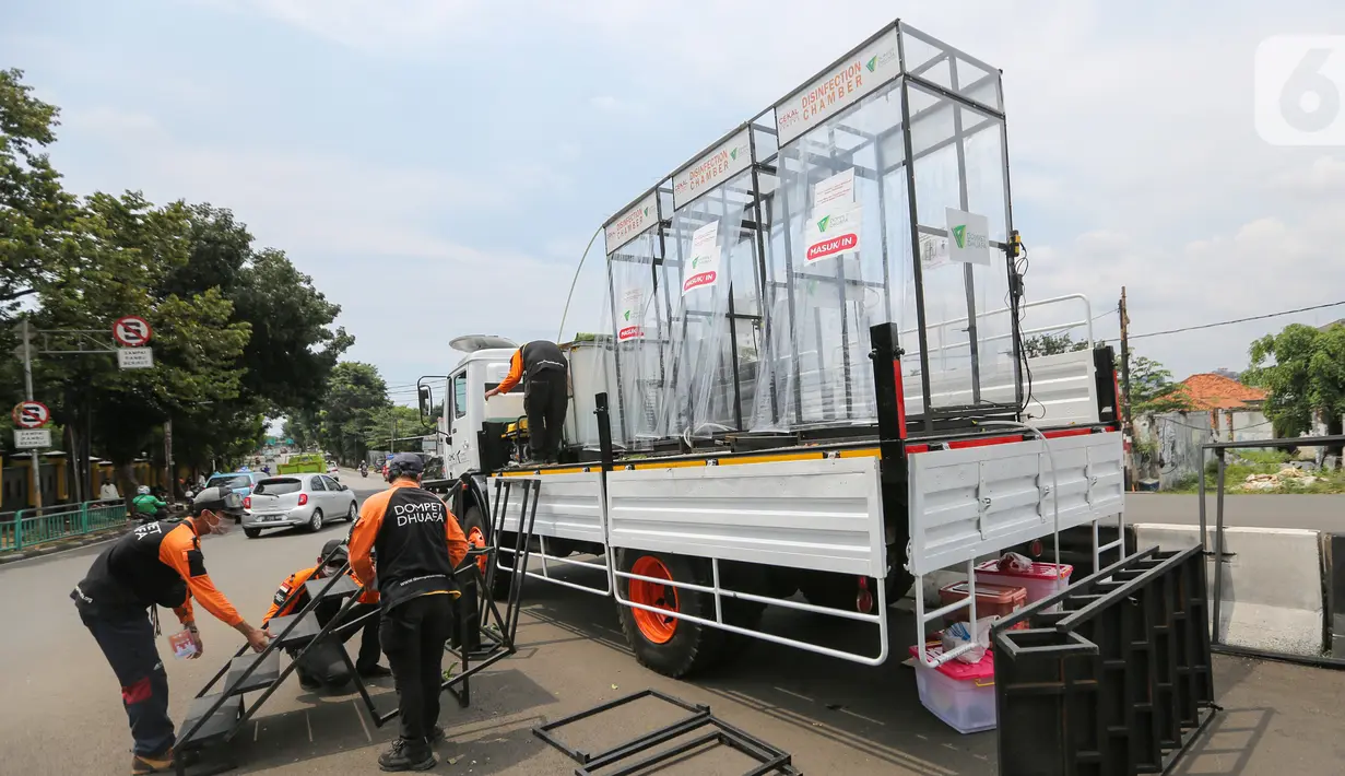 Relawan Dompet Dhuafa memasang tangga untuk masyarakat yang akan menggunakan bilik disinfektan chamber di CheCk Point PSBB, perbatasan Jakarta - Tangsel, Pasar Jumat, Kamis (16/4/2020). Disinfektan chamber aman bagi manusia karena menggunakan cairan antiseptik. (Liputan6.com/Fery Pradolo)