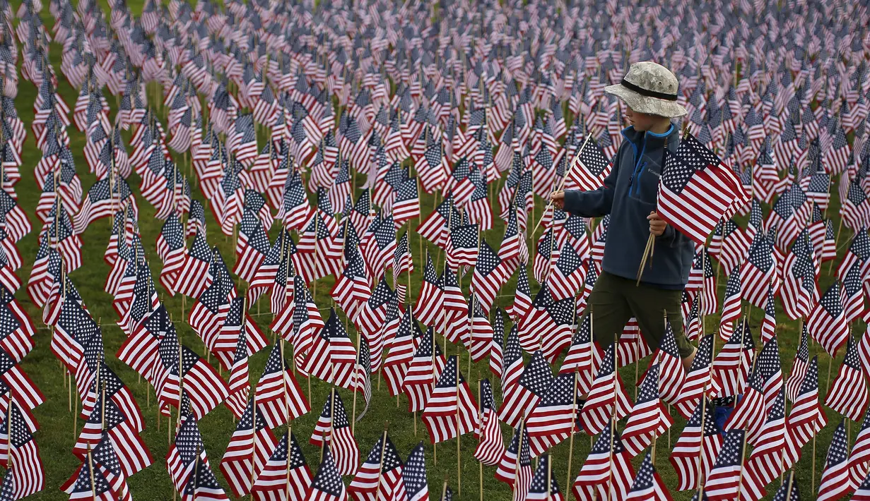 Seorang anak laki-laki berjalan di antara 3.000 bendera Amerika Serikat untuk mengenang sejumlah korban tewas dalam serangan 11 September 2001 di sebuah taman di Winnetka, Illinois, Kamis (10/9/2015). (REUTERS/Jim Young)