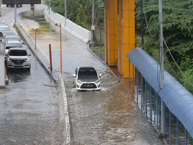 Sejumlah kendaraan melintasi Gerbang Tol Karang Tengah Barat 2 yang masih terendam banjir, Tangerang, Banten, Kamis (2/1/2020). Banjir setinggi betis orang dewasa masih menggenangi Gerbang Tol Karang Tengah Barat 2. (Liputan6.com/Angga Yuniar)