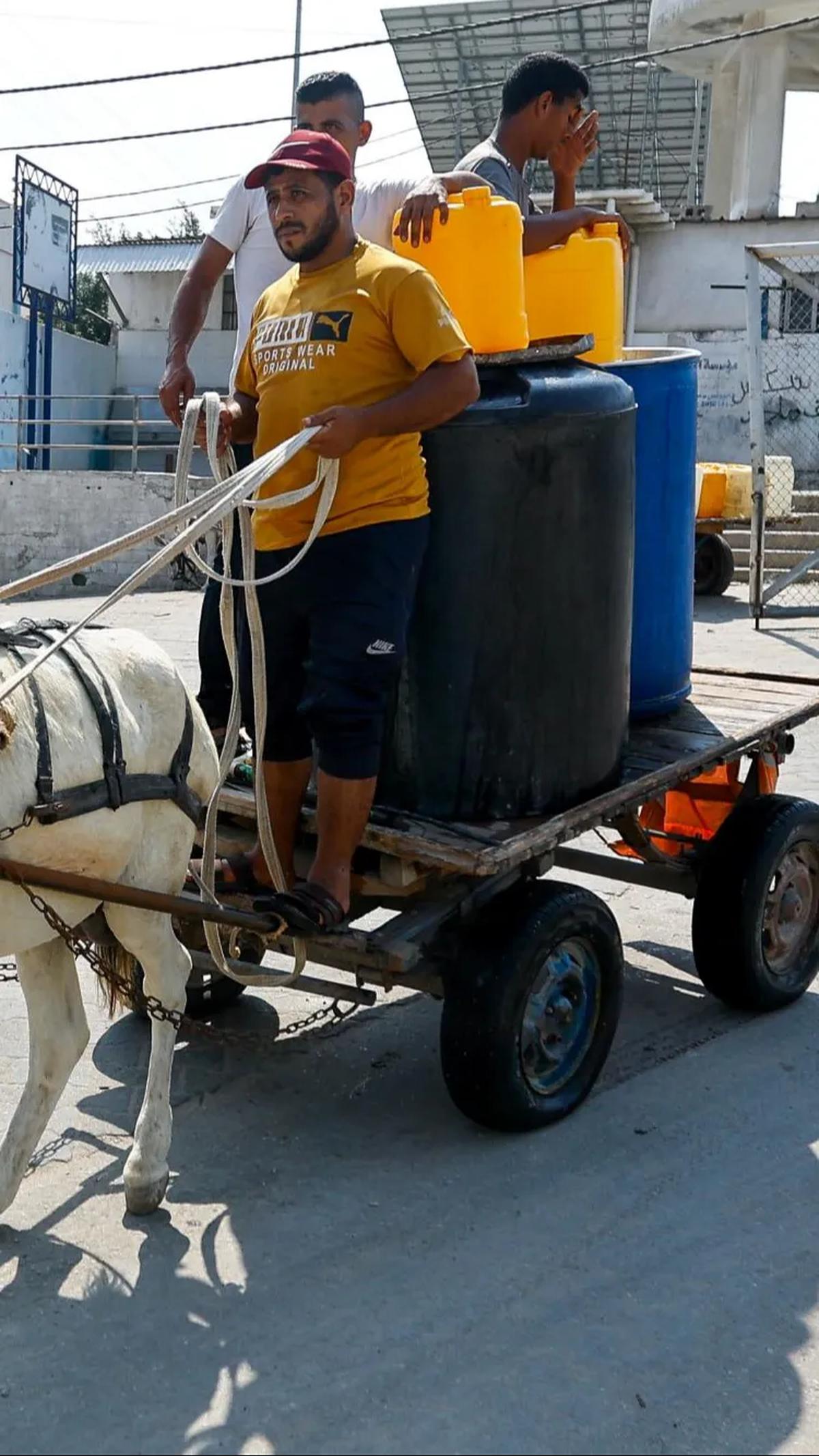 Jeriken, drum hingga tempat penampung air (toren) mereka bawa untuk mengisi air dari keran umum di tengah konflik Hamas dengan Israel di Khan Younis.