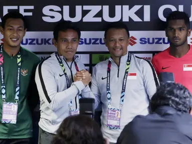 Pelatih Timnas Indonesia, Bima Sakti dan pelatih Singapura, Fandi Ahmad, bersalaman saat jumpa pers jelang laga Piala AFF 2018 di Stadion Nasional, Singapura, Kamis (8/11). Timnas akan berhadapan dengan Singapura. (Bola.com/M. Iqbal Ichsan)
