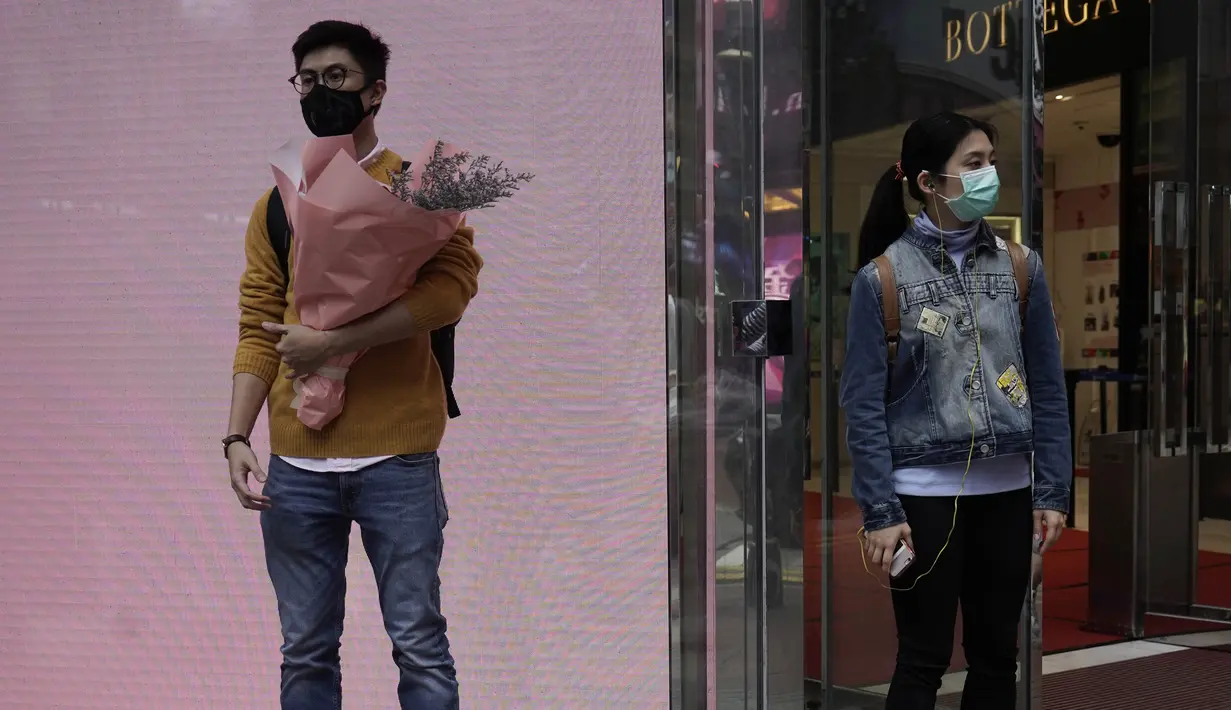 Seorang pria dan wanita mengenakan masker menunggu di sudut jalan pada Hari Valentine di Hong Kong, Jumat, (14/2/2020). Hari Valentine pada tanggal 14 Februari adalah sebuah hari di mana para kekasih dan mereka yang sedang jatuh cinta menyatakan cintanya. (AP Photo/Kin Cheung)