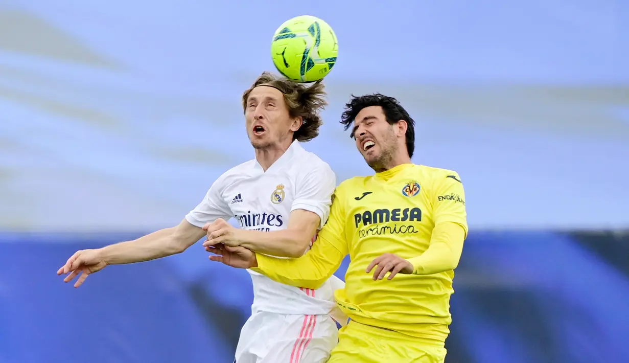 Pemain Villarreal, Daniel Parejo, duel udara dengan gelandang Real Madrid, Luka Modric, pada laga Liga Spanyol di Stadion Alfredo di Stefano, Sabtu (22/5/2021). Real Madrid menang dengan skor 2-1. (AFP/Javier Soriano)