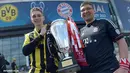 Dua orang suporter Borussia Dortmund dan Bayern Muencehen memegang replika tropi Liga Champions