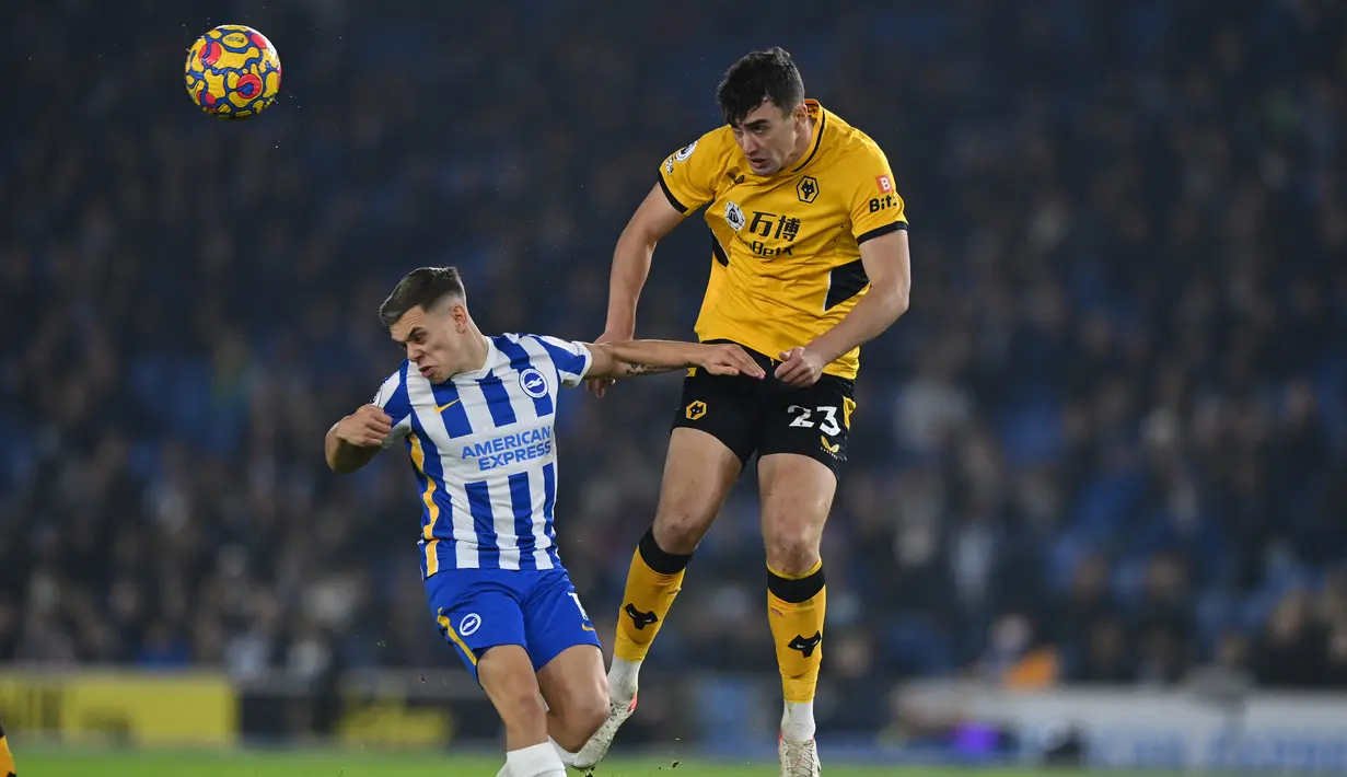 Bek Wolverhampton Wanderers, Max Kilman berebut bola dengan gelandang Brighton & Hove Albion, Leandro Trossard (kiri) pada laga pekan ke-17 Liga Inggris di Stadion Amex, Kamis (16/12/2021) dini hari WIB. Wolves mengalahkan Brighton & Hove Albion dengan skor 1-0. (Glyn KIRK / AFP)