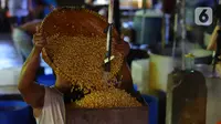 Pekerja menuang kedelai rebus saat proses pembuatan tahu di Jakarta, Senin (4/1/2021). Setelah melakukan mogok produksi selama 1 hingga 3 Januari 2021 akibat naiknya harga kacang kedelei impor, kini para perajin tahu mulai kembali beroperasi. (Liputan6.com/Angga Yuniar)