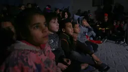 Anak-anak Palestina menonton sebuah film kartun yang ditayangkan pada layar putih berukuran besar yang dipasang di salah satu gang sempit di Kamp Pengungsi Nuseirat di Jalur Gaza tengah pada 26 Januari 2020. (Xinhua/Rizek Abdeljawad)