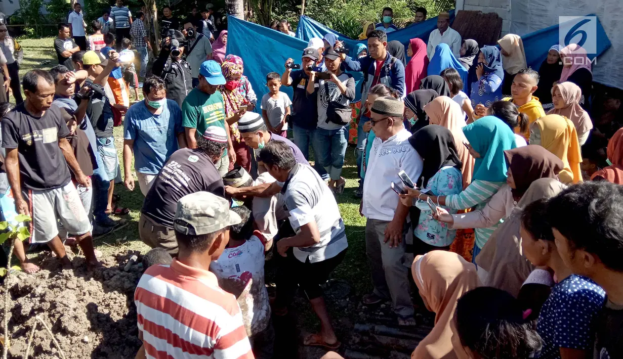 Kerumunan warga menonton pemindahkan jasad dari kuburan di Desa Toto Selatan, Kabupaten Bone Bolango, Gorontalo, Sabtu (12/1). Pemilik lahan tak terima lantaran keluarga jenazah menolak ajakan untuk memilih salah satu caleg. (Liputan6.com/Arfandi Ibrahim)