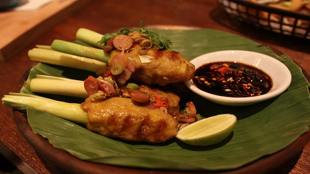 Sate Lilit Ayam disajikan dengan tangkai sereh, dan daun kecombrang sehingga aroma rempah meresap pada dagingnya.