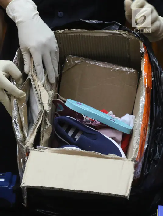 Petugas menunjukkan barang bukti kardus berisi sepatu sandal saat rilis penyelundupan 68 kg katinon dan 15.487 butir pil ekstasi dengan 11 tersangka di Kantor Pusat Bea Cukai, Jakarta, Senin (28/5). (Liputan6.com/Arya Manggala)