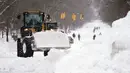 Para pekerja menggunakan alat berat untuk membersihkan salju dari Richmond Avenue, Buffalo, New York, Amerika Serikat, 26 Desember 2022. Pasukan Garda Nasional diminta membantu operasi penyelamatan yang diperumit salju tebal. (Derek Gee/The Buffalo News via AP)