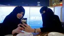 Dua wanita berhijab memainkan ponselnya saat berada di sebuah kafe di Riyadh, Arab Saudi (6/10). (REUTERS/Faisal Al Nasser)