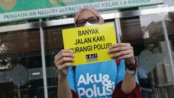 Aktivis membentangkan tulisan saat menunggu proses pengajuan gugatan warga untuk menuntut hak mendapatkan udara bersih di Pengadilan Negeri Jakarta Pusat, Kamis (4/7/2019). Mereka mengajukan gugatan warga negara kepada tujuh pihak tergugat. (Liputan6.com/Helmi Fithriansyah)