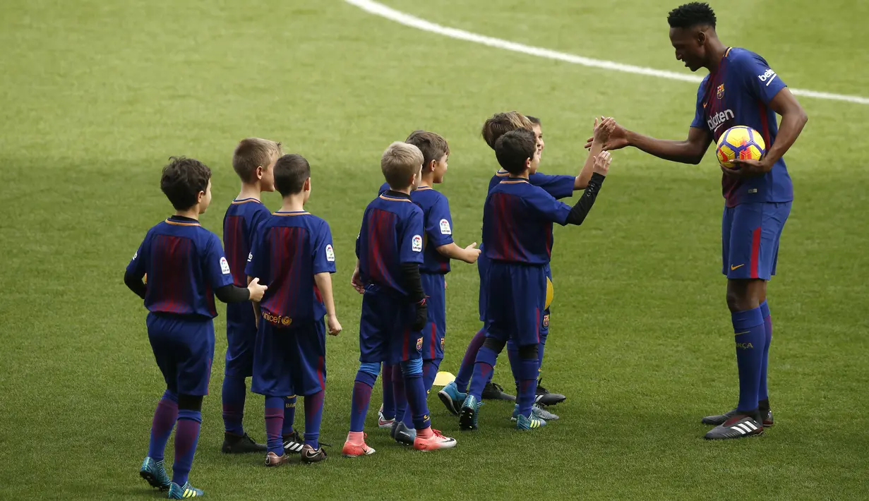 Bek anyar Barcelona, Yerry Mina menyapa anak-anak saat perkenalannya dengan para fans Blaugrana di Stadion Camp Nou, Barcelona, Spanyol, Sabtu (13/1). Yerry Mina mengaku gembira bisa berada di tim yang sama dengan Lionel Messi. (AP Photo/Manu Fernandez)