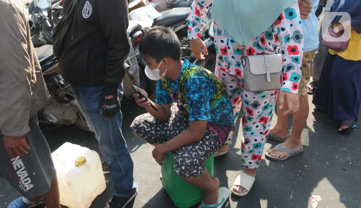 Seorang anak ikut antre untuk membeli minyak goreng curah pada distributor di Jalan MA Salmun, Bogor, Kamis (31/3/20222). Di tempat ini pembelian dibatasi hanya satu jerigen atau berisi 16 liter dengan harga Rp 256.000 atau Rp 16.000 per liter. (merdeka.com/Arie Basuki)