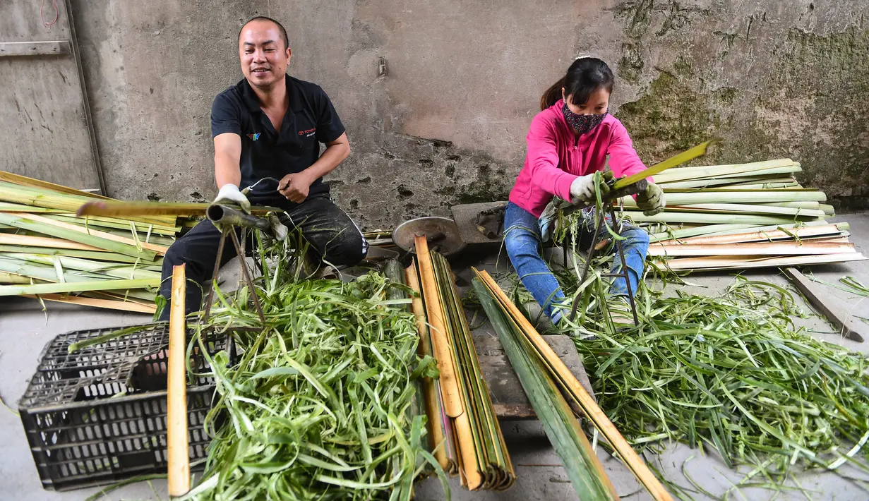 Warga memotong batang bambu untuk membuat dupa di desa Quang Phu Cau di pinggiran Hanoi, Vietnam, Rabu (12/1/2022). Penduduk desa sibuk menyiapkan ratusan ribu dupa untuk menyambut perayaan Tahun Baru Tet, Imlek versi Vietnam di Februari nanti. (Nhac NGUYEN/AFP)