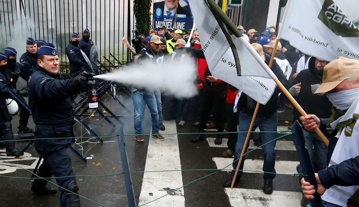 Polisi menyemprotkan merica saat aksi menolak Reformasi Pensiun di Brussels, Belgia, Selasa (15/11). Mereka menolak rencana pemerintah yang akan menaikkan usia pensiun dari 56 menjadi 63 tahun. (REUTERS / Yves Herman)