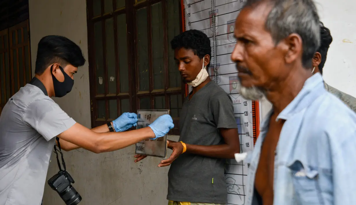 Seorang pria Rohingya (tengah) saat menjalani prosedur identifikasi oleh kepolisian Aceh di pusat penampungan sementara bekas kantor Imigrasi Punteuet di Lhokseumawe, Aceh Utara (26/6/2020). (AFP Photo/CHAIDEER MAHYUDDIN)