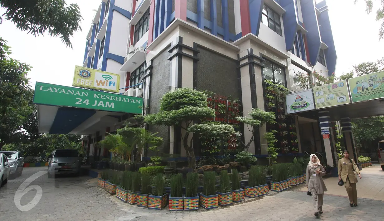 Dua orang pegawai berjalan di halaman Puskesmas Kecamatan Kebon Jeruk, Jakarta, Selasa (18/10). Selain menyediakan charger box disetiap lantai, puskesmas ini juga disediakan free wifi yang bisa dimanfaatkan para pasien. (Liputan6.com/Immanuel Antonius)