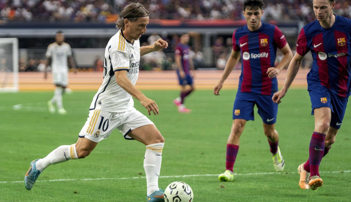 Gelandang Real Madrid Luka Modric (10) menggiring bola melawan gelandang FC Barcelona Frenkie de Jong (kanan) dan bek Andreas Christensen dalam laga pramusim bertajuk Soccer Champions Tour di AT&T Stadium, Texas, Amerika Serikat, Minggu (30/7/2023) dini hari WIB. (AP Photo/Jeffrey McWhorter)