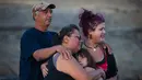 Keluarga menangisi rumah mereka yang hangus akibat kebakaran hutan di Ashcroft First Nation, British Columbia, Kanada, (9/7). Sekitar 14 ribu warga terpaksa mengungsi akibat kebakaran tersebut. (Darryl Dyck/The Canadian Press via AP)