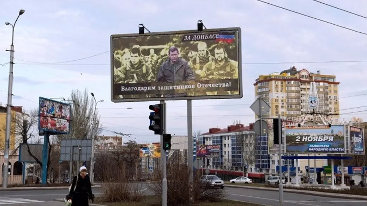Seorang wanita berjalan di bawah papan reklame di Donetsk yang menampilkan Alexander Zakharchenko, pemimpin kelompok separatis