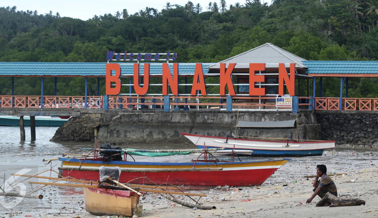 Warga duduk di pinggir pantai dekat tulisan 'Welcome to Bunaken' di Pulau Bunaken, Manado, Sabtu (17/12). Pemprov Sulut gencar melakukan promosi pariwisata dengan tujuan mendatangkan turis sebanyak mungkin hingga ke Tiongkok. (Liputan6.com/Fery Pradolo)