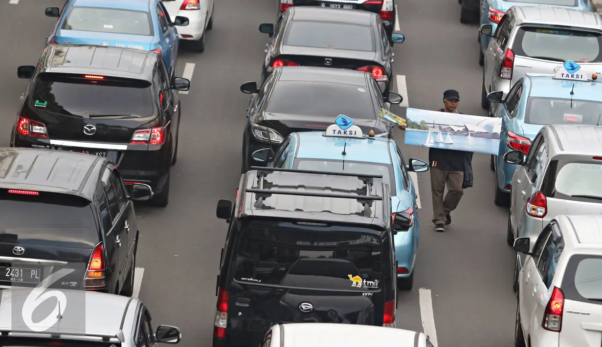 Pedagang asongan menjajakan dagangannya di tengah kemacetan kawasan Harmoni, Jakarta, Selasa (19/4). Kemacetan yang semakin parah di Ibukota menjadi keuntungan tersendiri bagi para pedagang asongan untuk mencari nafkah. (Liputan6.com/Immanuel Antonius)