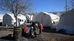 Beberapa anak-anak bermain di sebuah kamp pengungsi Suriah yang didirikan oleh lembaga bantuan Turki AFAD di distrik Islahiye, Gaziantep, Turki, Rabu (15/2/2023). Hingga kini, tim penyelamat terus berjuang melawan waktu untuk menyelamatkan korban yang masih tertimbun reruntuhan. (OZAN KOSE/AFP)