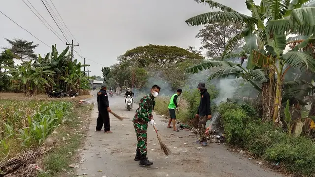 Serka Mashudi dan warga membersihkan sampah yang dibuang di tengah jalan raya, Rabu 19/5/2021. (Foto: Liputan6.com/Kusfitria Marstyasih)