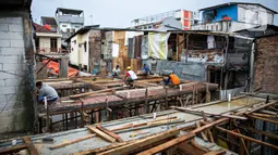 Para pekerja menyelesaikan pembangunan rumah panggung di dekat bantaran Kali Ciliwung, Kampung Melayu, Jakarta, Rabu (7/4/2021). Pemerintah Provinsi DKI Jakarta melakukan renovasi terhadap 40 hunian warga Kampung Melayu menjadi rumah panggung. (Liputan6.com/Faizal Fanani)