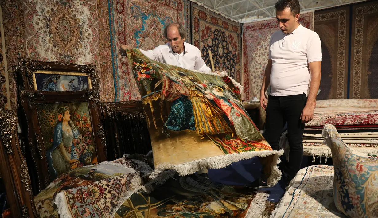 Pedagang memamerkan karpet tenun dagangannya kepada pengunjung pameran di Teheran, Iran, Kamis (29/8/2019). Eksportir karpet Iran kehilangan pasar AS setelah Presiden Donald Trump menjatuhkan sanksi berat terhadap negara tersebut. (AP Photo/Vahid Salemi)