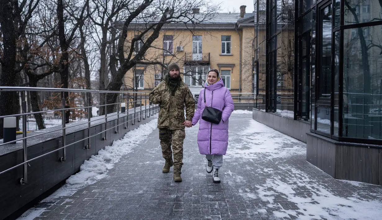 Tentara Ukraina Vitalii Khroniuk dan rekannya Anna Sokurenko berjalan di jalan setelah kunjungan mereka ke klinik kesuburan di Kiev, Ukraina, 4 Februari 2023. Saat Khroniuk terbaring telungkup di tanah berlindung dari tembakan artileri Rusia, prajurit Ukraina hanya memiliki satu penyesalan : Dia belum pernah punya anak. (AP Photo/Evgeniy Maloletka)